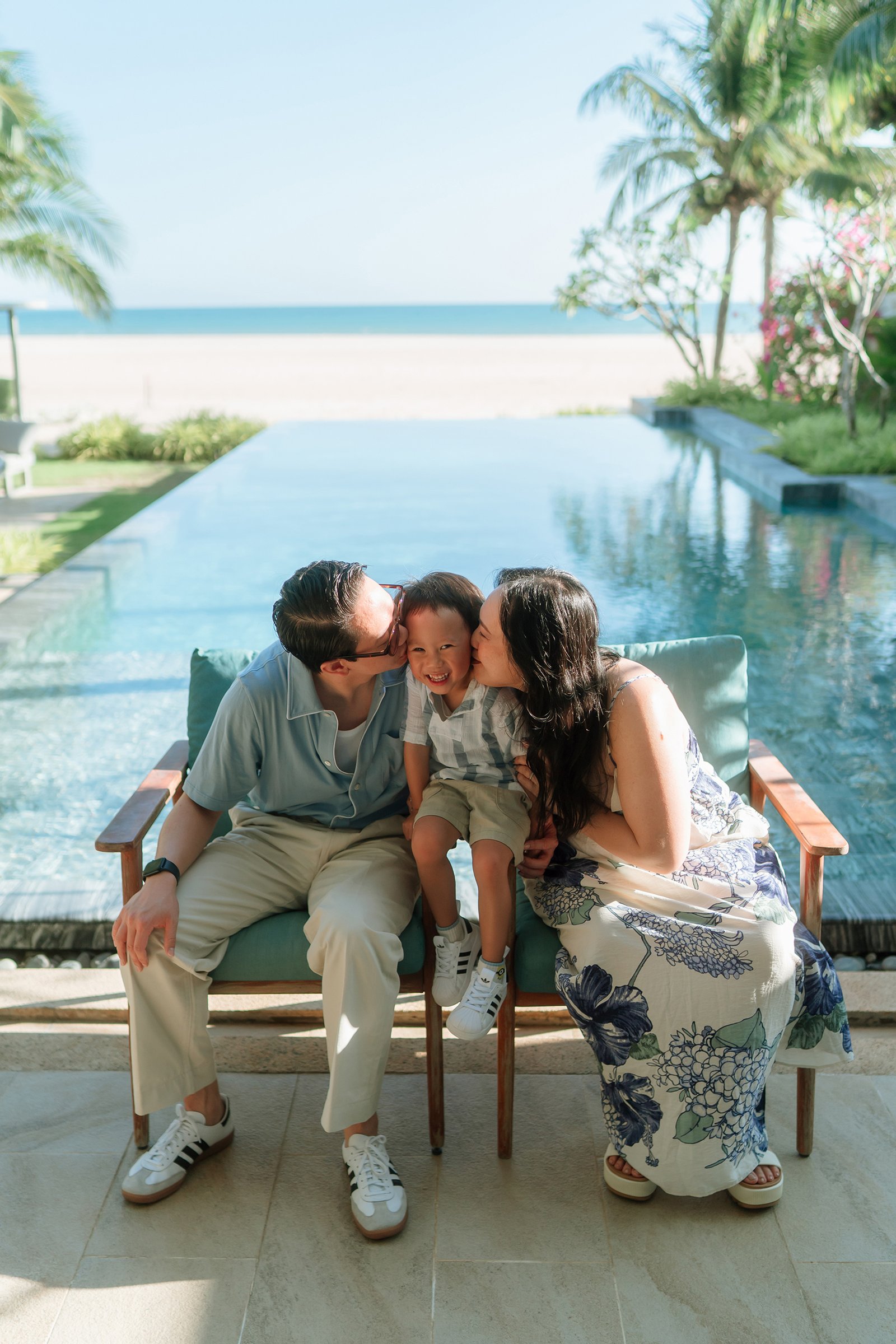 Family of three in front of a pool with oceanview